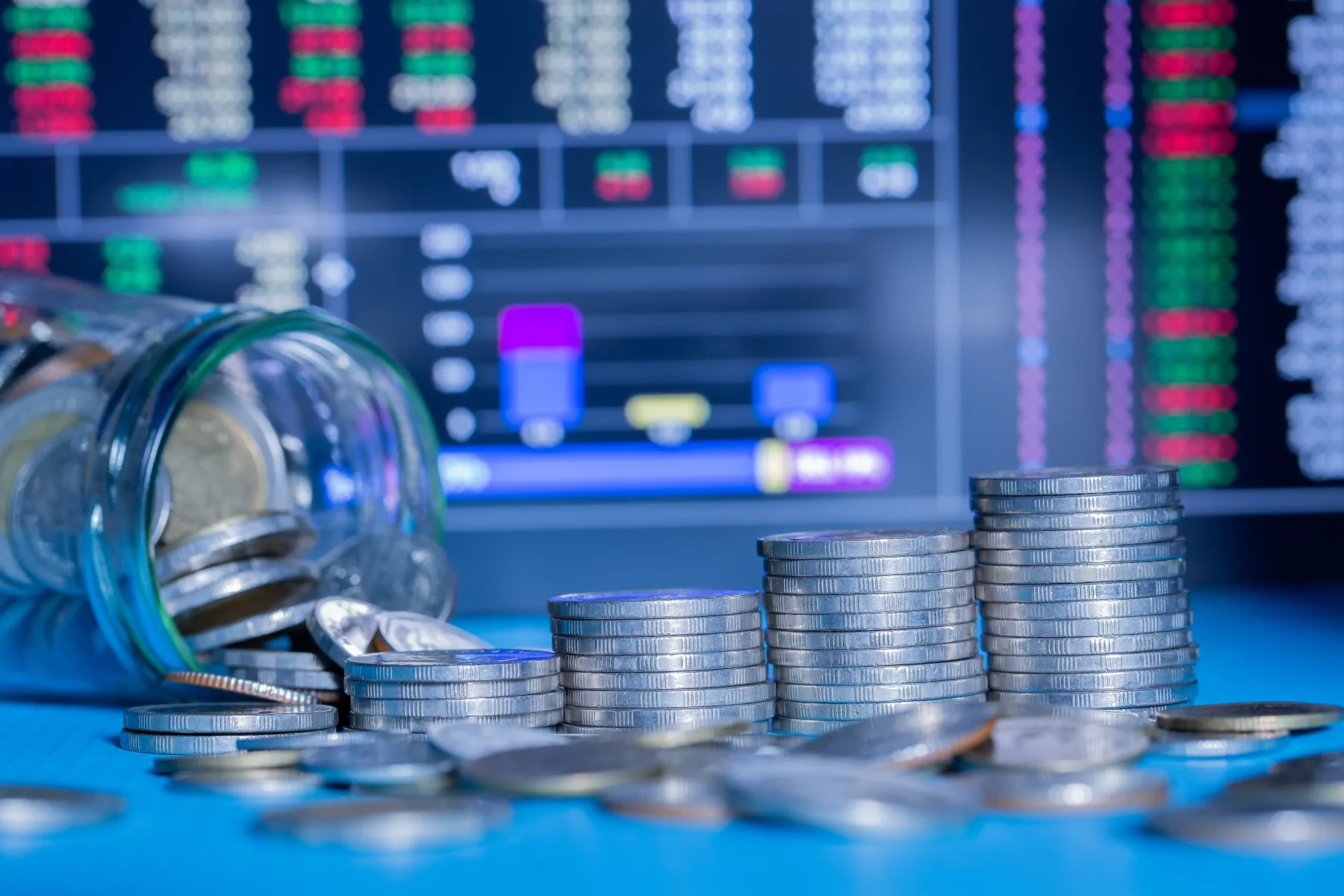 Stacks of coins in front of financial market data for banking and finance professionals